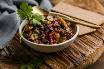 Olive tapenade with herbs and olive oil in a rustic bowl