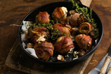 Juicy baked champignons wrapped in crispy bacon with creamy cheese filling, perfect party snack.
