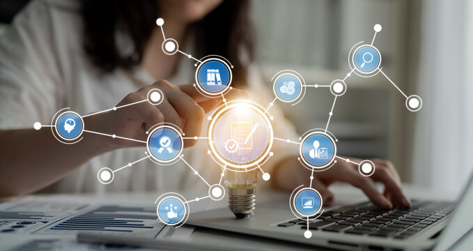 A modern workspace featuring a person working on a laptop, with a glowing light bulb and digital icons symbolizing creativity and business growth surrounding them. Crux