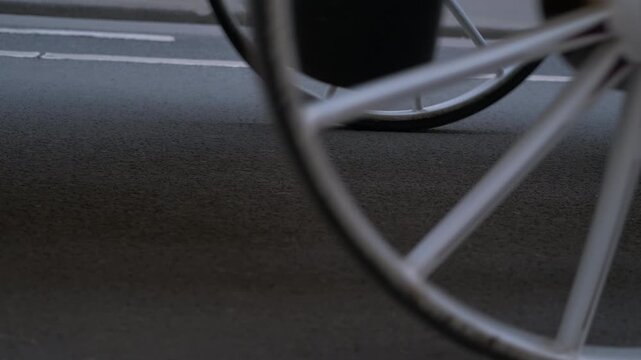 Horse pulling carriage walking on asphalt road. Closeup of hooves and wheels in motion showcases a horse pulling a carriage along a paved road.