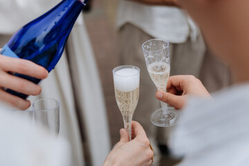 Pouring sparkling wine into plastic flutes during outdoor celebration toast