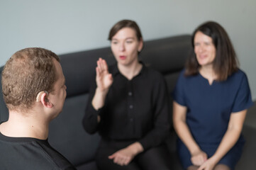 A man and two women are talking in Russian sign language. 