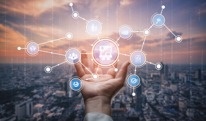 A hand is shown gesturing toward a digital network display over a city skyline at sunset. The visual represents modern technology and communication concepts. Tessel