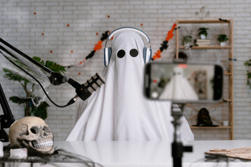 Funny ghost in a white sheet recording a podcast or blog