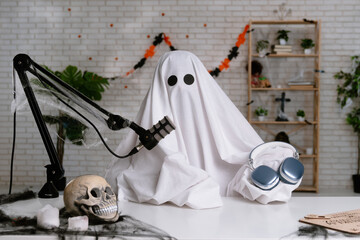 Funny ghost in a white sheet recording a podcast or blog