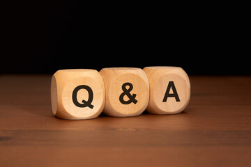 wooden blocks with the letters Q and A on a wooden surface with a dark background