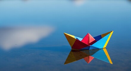 Colorful origami paper boat floating on calm water surface with reflection and dreamy sky background background