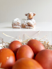 Traditional Easter still life with a lamb-shaped cake and red painted eggs in a straw nest