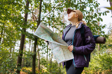 Woman hiker reading map during forest trekking