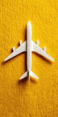 A white paper airplane model rests atop a vibrant yellow surface.