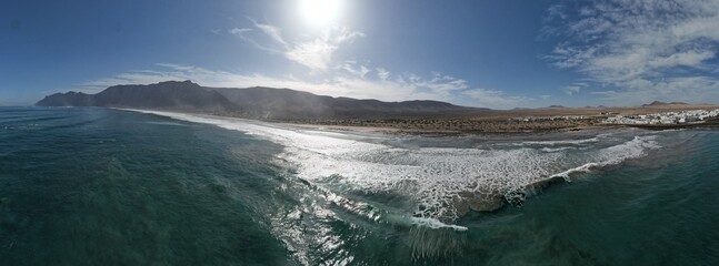 Naklejka premium Famara coastal town with sandy beaches on Lanzarote island captured in aerial panoramic view Canary islands Spain