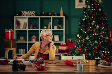Senior woman looking at christmas tree while preparing decorations