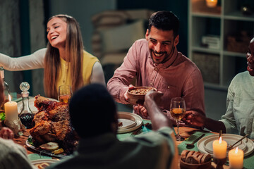 Friends sharing food, laughing and having fun at thanksgiving dinner