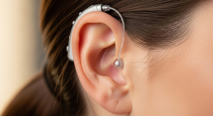 A modern, discreet hearing aid behind a woman's ear, symbolizing technological advancement to improve the quality of life