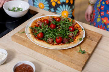 Delicious Freshly Made Pizza topped with Cherry Tomatoes and Arugula for everyone to enjoy