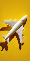 A stylized white airplane model casts a shadow on a bright yellow backdrop.