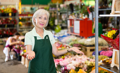 Portrait of benevolent owner of the flower market against the background of bouquets and potted flowers