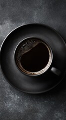 Rich dark coffee in a sleek black ceramic cup and saucer, presented on a dark gray stone surface, evokes a sophisticated and minimalist mood.