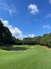Sunny golf course fairway with sand bunkers and blue sky