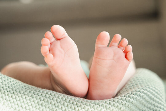 bottom of white newborn baby feet on a soft green blanket
