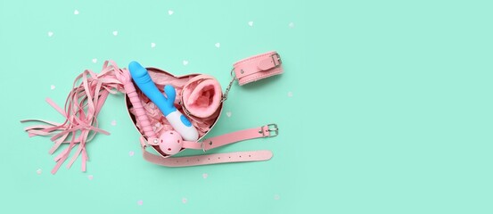 Heart-shaped box with sex toys on turquoise background with space for text