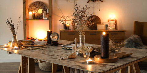 Burning candles with magic attributes on table in witch's room