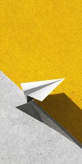 A simple paper airplane floats against a backdrop of contrasting yellow and gray textured surfaces.