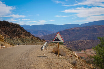 Winding mountain road with a guardrail winds through the rugged, arid landscape on a sunny day....