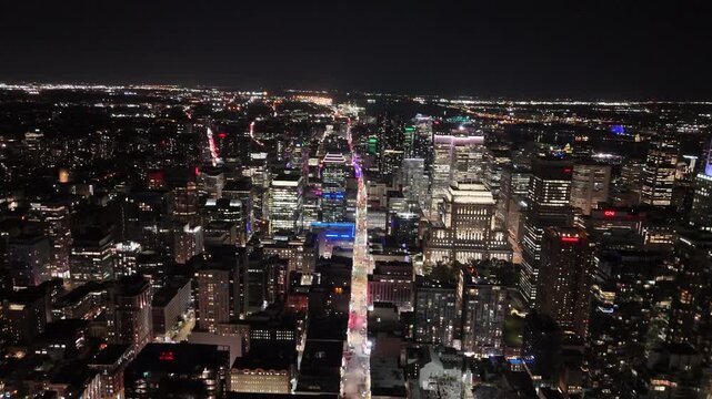 Drone ascends over CIBC Tower and Sheraton in downtown Montreal at night, revealing rooftop views, bridge lights, traffic, and the rotating beacon of 1000 de La Gaucheti&egrave;re