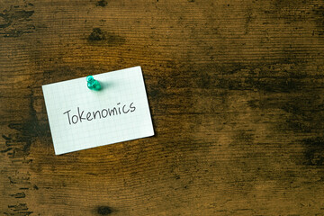 There is a piece of paper with the word Tokenomics. It is as an eye-catching image.
