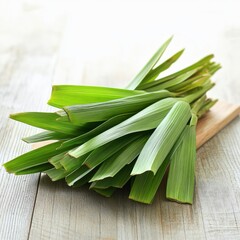 Fresh green pandan leaves arranged neatly on a wooden surface, showcasing their vibrant color and texture.