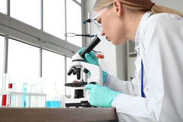 Female scientist looking through microscope in laboratory
