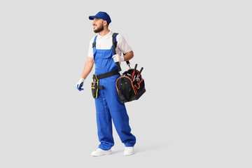 Male worker with tool bag walking on white background