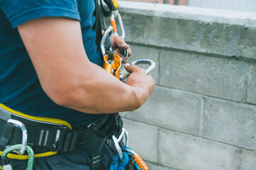 Firefighter and rescuer putting on harness, carabiners, and rappelling equipment to practice rappelling down a multi-story building.