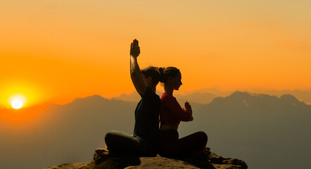 Dark silhouette of a man and woman in professional yoga poses for yoga background
