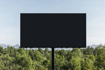 A large empty billboard stands above a green treeline against a clear blue sky, inviting attention and future messaging in outdoor advertising.