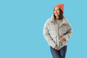 Fototapeta premium Young woman in stylish puffer jacket on blue background