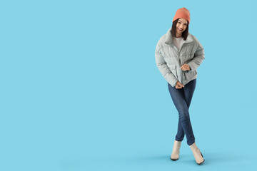 Young woman in stylish puffer jacket on blue background