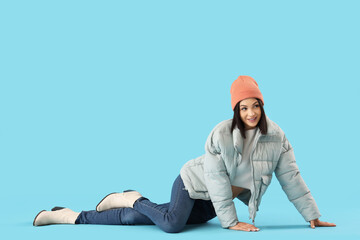 Young woman in stylish puffer jacket on blue background