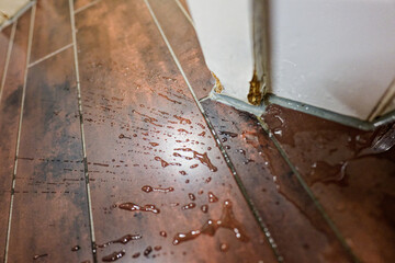 Spilled water on boards by tiled wall and warped divider