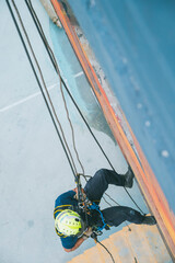 
Firefighter rescuer descending a massive wall using a rappelling device in a multi-story building, wearing protective gear such as a helmet, harness, and carabiners.