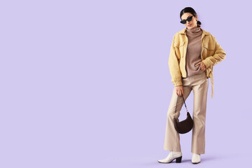 Young woman in stylish jacket on lilac background