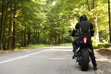 Young man in helmet driving modern motorcycle outdoors, back view. Space for text © New Africa