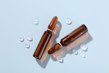 Glass ampoules with cosmetic product on light blue background, flat lay