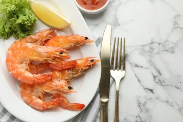 Delicious seafood dish. Tasty grilled shrimps served with lemon, lettuce and sauce on white marble table, flat lay. Space for text