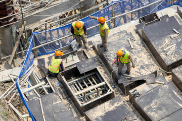 Group of construction workers wearing safety vests and helmets working on a building framework.