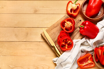 Bowls and cutting board with red bell peppers on wooden background