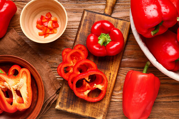 Cutting board and bowls with red bell peppers on wooden background