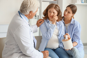 Obraz premium Crying pregnant lesbian couple with fertility doctor after IVF in clinic