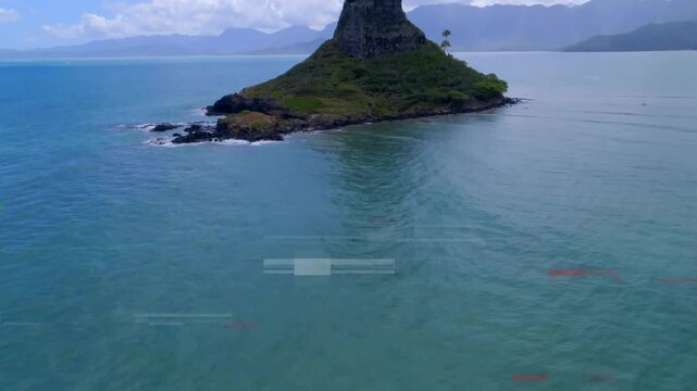 Camera starting movement revealing islet rising over sea with palm trees to frame misty mountains